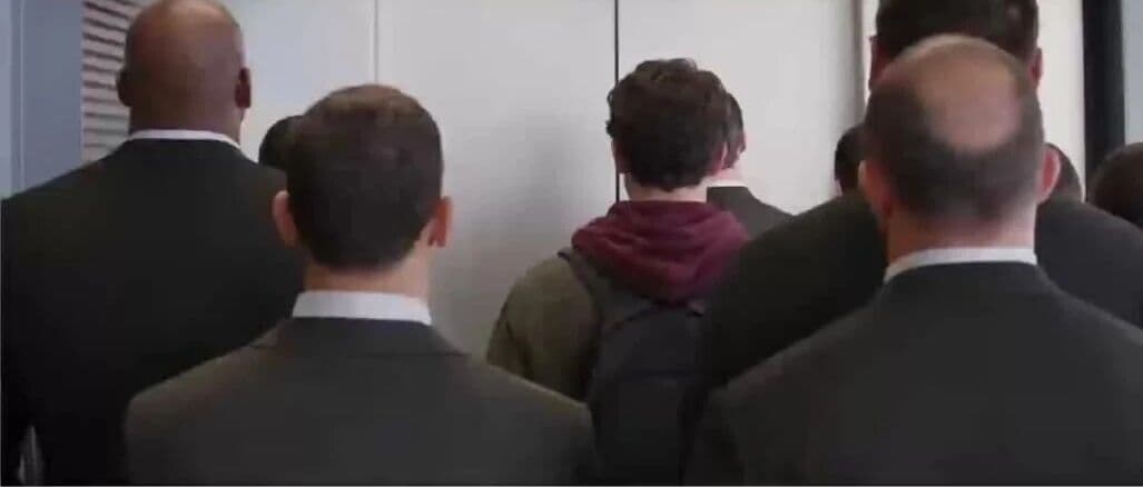 Video still from the Kling 4.0 elevator fight scene with the hoodie-wearing man surrounded by suited attackers